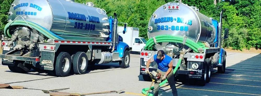 Rosano Davis technician pumping a septic tank with two tanker trucks on site